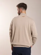 Campera color beige de tejido de punto con cierre frontal y cuello alto.