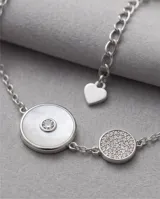 Pulsera de plata italiana 925 con cadena de eslabones finos, presenta dos dijes circulares, uno con incrustación de nácar y centro de circonia, y otro pequeño con pavé de circonias. Incluye cadena de alargue con dije final en forma de corazón.