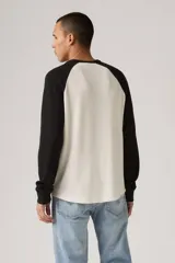 Remera térmica de manga larga con diseño raglán, color blanco en el cuerpo y negro en las mangas. Presenta un tejido texturizado tipo waffle y cuello redondo.