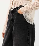 Pantalón baggy de jean color gris oscuro, de tiro medio y corte holgado, con bolsillos frontales y traseros.