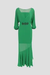 Vestido largo color verde esmeralda, con escote cuadrado y mangas 3/4 abullonadas. Presenta un cinturón con apliques de flores y una falda con paneles de gasa y volados asimétricos.