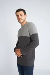 Sweater de punto con diseño color block en tonos gris claro y gris oscuro, de cuello redondo y manga larga. Presenta un pequeño logo bordado en el pecho.