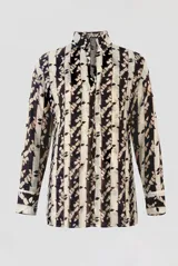 Blusa manga larga de corte recto con cuello camisero y escote en V profundo. Presenta un estampado vertical de rayas con motivos abstractos en tonos marrón oscuro sobre fondo beige.