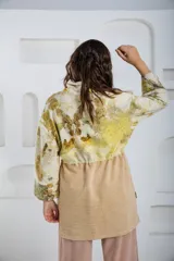 Buzo oversize color crema con estampado de hojas en tonos verde y amarillo, cuello alto con medio cierre metálico y jareta en la cintura para ajustar.