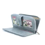 Billetera larga de cuerina color celeste con efecto desgastado, solapa con broche a presión y placa metálica con la marca grabada. Cuenta con compartimento posterior con cierre metálico.