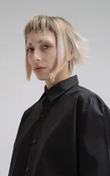 Camisa negra de manga larga, confeccionada en poplín de algodón. Presenta un calce oversize, cuello camisero, cierre frontal de botones y dos bolsillos cuadrados superpuestos en el lado derecho del pecho.