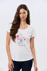 Remera blanca de manga corta y cuello redondo, con estampa frontal de flores en tonos rosados dentro de un frasco de vidrio y detalles de letras bordadas.
