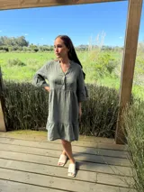 Vestido corto de lino color beige claro, con cuello mao, escote con botones de nácar, mangas tres cuartos con volados y ruedo con volado.