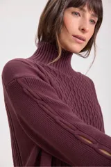Sweater de punto color bordó con cuello alto y diseño de trenzas en el frente y las mangas. Presenta un corte holgado y largo, con puños y ruedo acanalados.