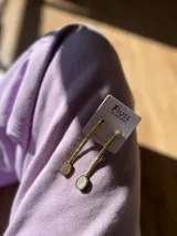 Aros colgantes hechos a mano en bronce, con barra texturada y dije circular de nácar.