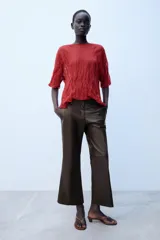 Pantalón de tiro medio confeccionado en 100% piel de color marrón, con diseño flare y costuras decorativas.