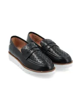 Mocasines negros con diseño calado en la parte superior, banda frontal clásica y suela de plataforma dentada en color blanco.