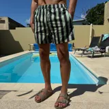 Short de baño con diseño de rayas verticales en color verde menta y negro. Cuenta con cintura elástica con cordón ajustable y un parche circular con logo en la parte inferior.