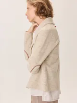 Saco de lana hervida color negro, con cuello solapa, cierre frontal de botones rústicos y bolsillos laterales. Presenta un diseño clásico con coderas y textura artesanal.