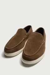 Mocasines casuales para hombre, fabricados en piel con acabado en serraje color marrón, de corte liso con detalle de bordón y suela blanca a contraste.