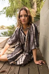 Vestido camisero con cuello a la base y mangas al codo, con botones al frente y estampado tie dye en tonos grises y blancos.