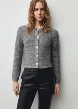 Chaqueta de punto con acabado brillante de lúrex, cuello redondo y cierre frontal con botones joya. Presenta un diseño recto de manga larga.