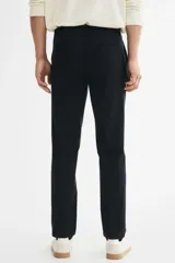 Pantalón sastrero de corte slim fit y diseño liso, color negro, con pliegues frontales, bolsillos laterales y cierre con botón.