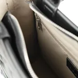 Bolso tote negro de cuero sintético acolchado con diseño rectangular. Tiene doble asa corta y correa larga regulable extraíble. El acceso es con cierre y cuenta con un bolsillo interno con cierre y dos abiertos.