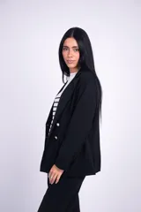 Blazer negro levemente largo, con solapas de muesca, doble botonadura con botones metálicos dorados, hombreras y bolsillos delanteros ribeteados con solapa.