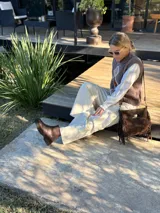 Chaleco tejido de punto en color chocolate, con cuello redondo y diseño sin mangas. Presenta un aplique frontal decorativo compuesto por tres figuras en forma de rombo en tonos tierra, bordeadas con hilo crudo.