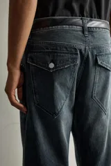 Jeans loose fit de hombre en denim de algodón color gris oscuro con efecto lavado. Presenta perneras con costuras giradas hacia los tobillos, tiro medio, cierre frontal con botones y bolsillos frontales con bolsillo cerillero.