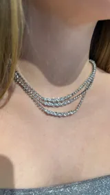 Gargantilla de tres niveles compuesta por cadenas de cristales brillantes engarzados en metal plateado.