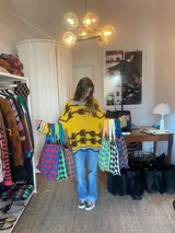 Bolso tejido con patrón de damero en varios colores, con asas de tela.