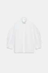 Camisa blanca de algodón de la colección ZW Collection de Zara, con cuello alto, mangas abullonadas por debajo del codo y cierre frontal con botones ocultos por solapa.