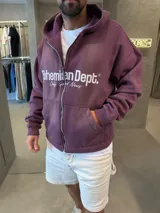 Campera con capucha y cierre frontal, color uva, con corte boxy y estampa frontal con texto en blanco.