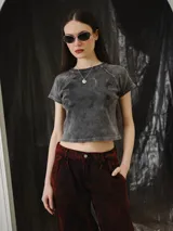 Remera baby tee de algodón gris con efecto stone wash, calce ajustado al cuerpo y largo corto, con mangas cortas y cuello redondo. Cuenta con un gran estampado en serigrafía de un animal mitológico en la parte frontal.