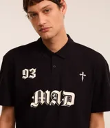 Remera de corte boxy confeccionada en algodón, con cuello polo y cierre frontal de botones. Presenta un diseño estampado en el frente con el número 93, una cruz y la palabra MAD en tipografía gótica.
