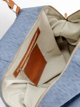 Bolso de viaje grande de cuero marrón con detalles en cuero negro, doble asa de mano y tiras decorativas verticales.
