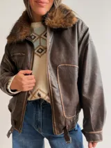 Campera estilo bomber de efecto cuero en color chocolate, con cuello de pelo sintético desmontable, cierre frontal, bolsillos laterales amplios y cintura elástica con ajuste lateral.