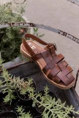Sandalias tipo huarache de cuero con diseño de tiras entrelazadas, punta cerrada y cierre con hebilla lateral. Cuentan con suela plana y plantilla con logo grabado.