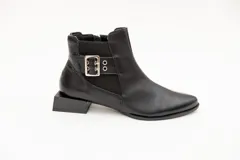 Botín de cuero negro con elásticos laterales, aplique metálico con ojales y cierre lateral con cremallera. Taco cuadrado desfasado de 3 cm.