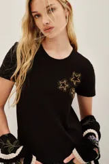 Remera de algodón color negro, de corte clásico y manga corta, con detalle de estrellas bordadas en hilo dorado y pequeñas aplicaciones brillantes en el pecho.