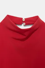 Top halter asimétrico de color rojo, confeccionado en tejido elástico, con cuello alto y cierre posterior con botones.