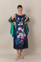 Vestido italiano azul con estampado floral en tonos rosa, blanco y verde. Presenta detalle de encaje en el escote, corte a la cintura y falda con tablas.