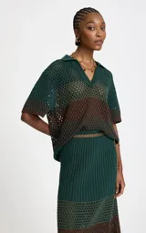 Camisa de punto calado con rayas horizontales en verde oscuro y marrón, cuello polo en V, mangas cortas holgadas y ribetes acanalados en los puños y el bajo.
