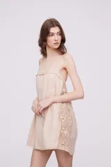 Vestido corto color marfil con breteles finos, escote recto y detalle de puntilla en los laterales y ruedo.