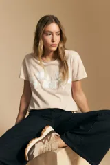 Remera de manga corta color negro con cuello redondo y un aplique bordado de flores y hojas en color beige claro en el centro del pecho.