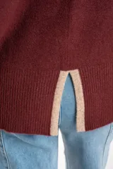 Polera de punto con calce oversize, cuello alto y mangas largas. Presenta un diseño en color negro con franjas laterales en las mangas y detalle en el cuello en tono bronce con acabado brillante.