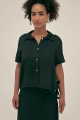 Camisa negra de manga corta con cuello camisero y botones de conchas naturales. El tejido lino-tencel es ideal para conseguir un look atemporal y natural.