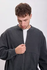 Campera deportiva gris oscuro de corte bomber con cierre frontal y cuello redondo. Confeccionada en tejido de punto con efecto lavado.