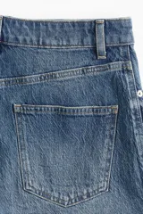 Short pollera de cinco bolsillos en denim azul con efecto deslavado, tiro alto, cierre de cremallera y botón metálico.
