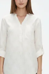 Blusa de viscosa color bordó, con cuello en V, cierre frontal parcial con botones, mangas tres cuartos y bolsillo aplicado en el pecho.