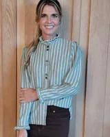 Camisa de manga larga a rayas verticales blancas y verdes, con cuello alto tipo lechuguilla y puños con volados. Presenta cierre frontal con doble botón y diseño de corte recto.