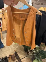 Chaleco de cuero color camel con doble botonadura y corte clásico.