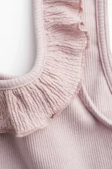 Musculosa corta de ajuste entallado en punto acanalado, color rosado pálido. Presenta escote cuadrado con un ribete de volado fruncido que se extiende sobre los breteles.